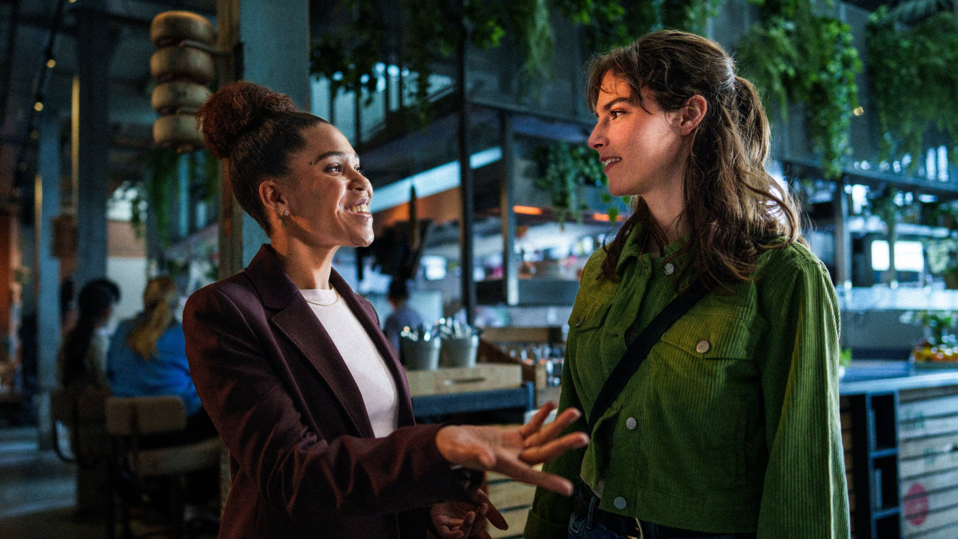 Twee vrolijke horecamedewerkers van HMSHost die samenwerken achter de counter van een drukke luchthavenlocatie, uitstralend van teamspirit en werkplezier.